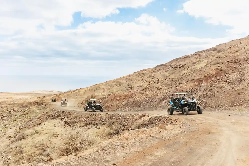Buggies driving across volcanic desert landscape