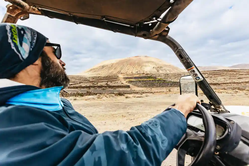 Buggy driver steering across volcanic desert landscape