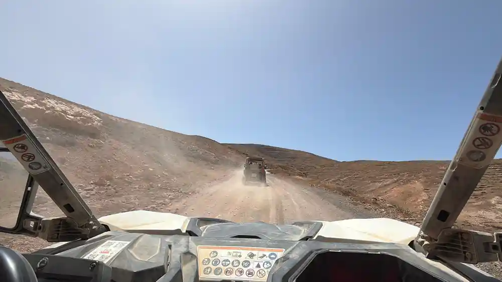Buggy driving on dusty mountain road in sparse terrain