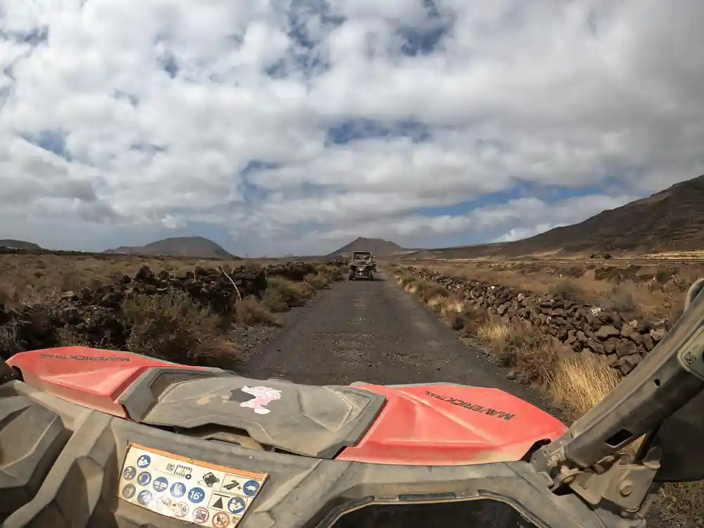 Buggy driving on dusty road with vehicles ahead