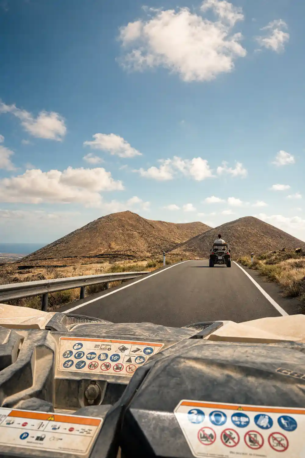 Buggy hood view driving on black asphalt road toward volcano