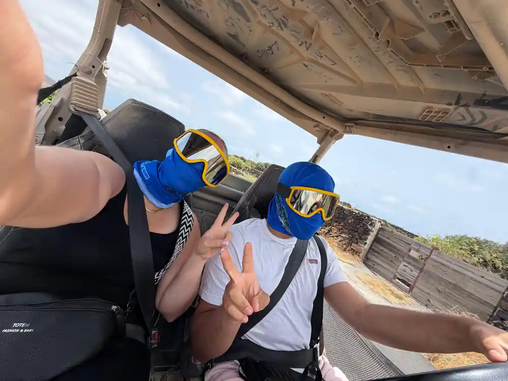 Buggy hood view with hands adjusting safety harness on passenger