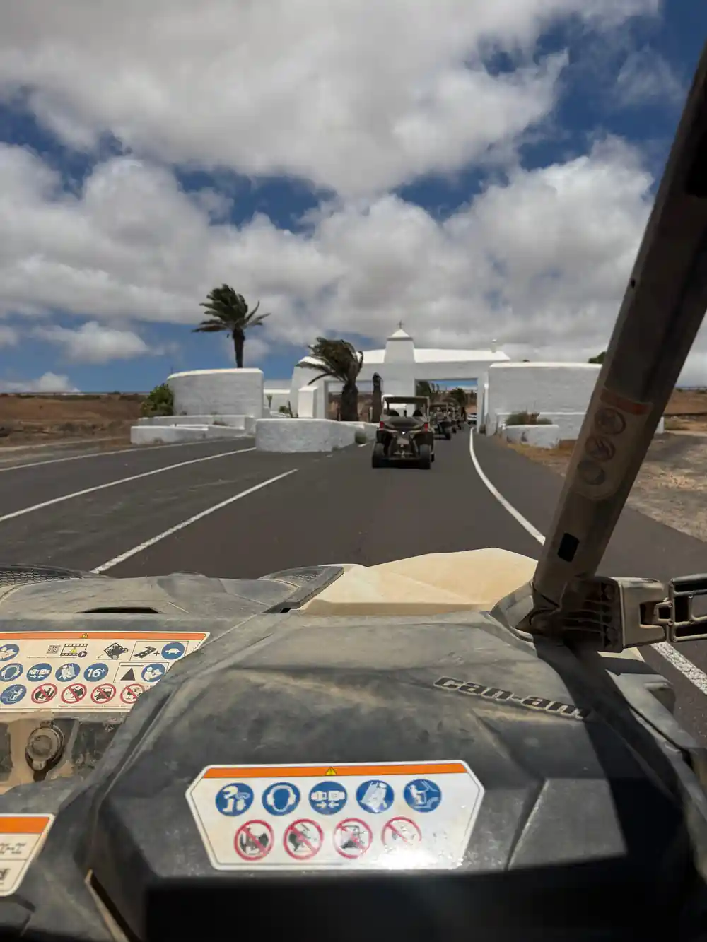 Buggy interior driving past white building with palms