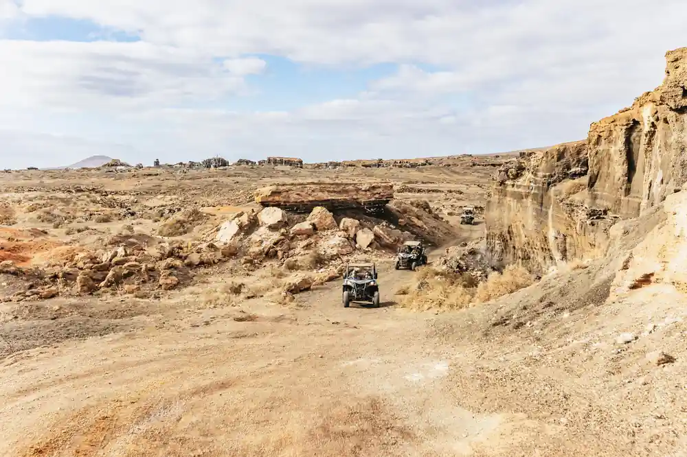 Buggy parked beneath rocky volcanic cliff formation