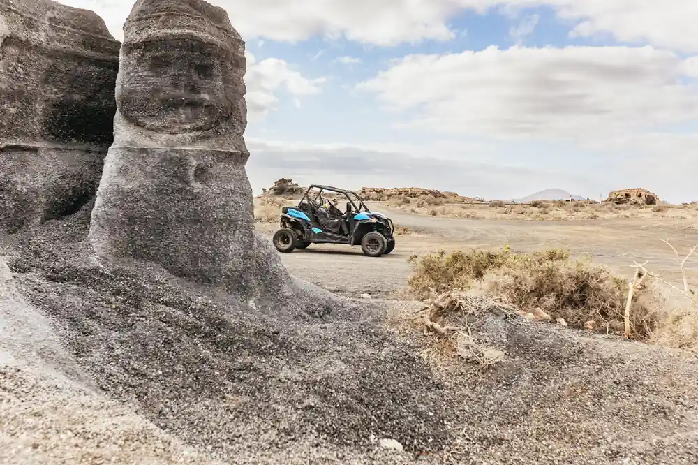Buggy parked beside large volcanic rock formation