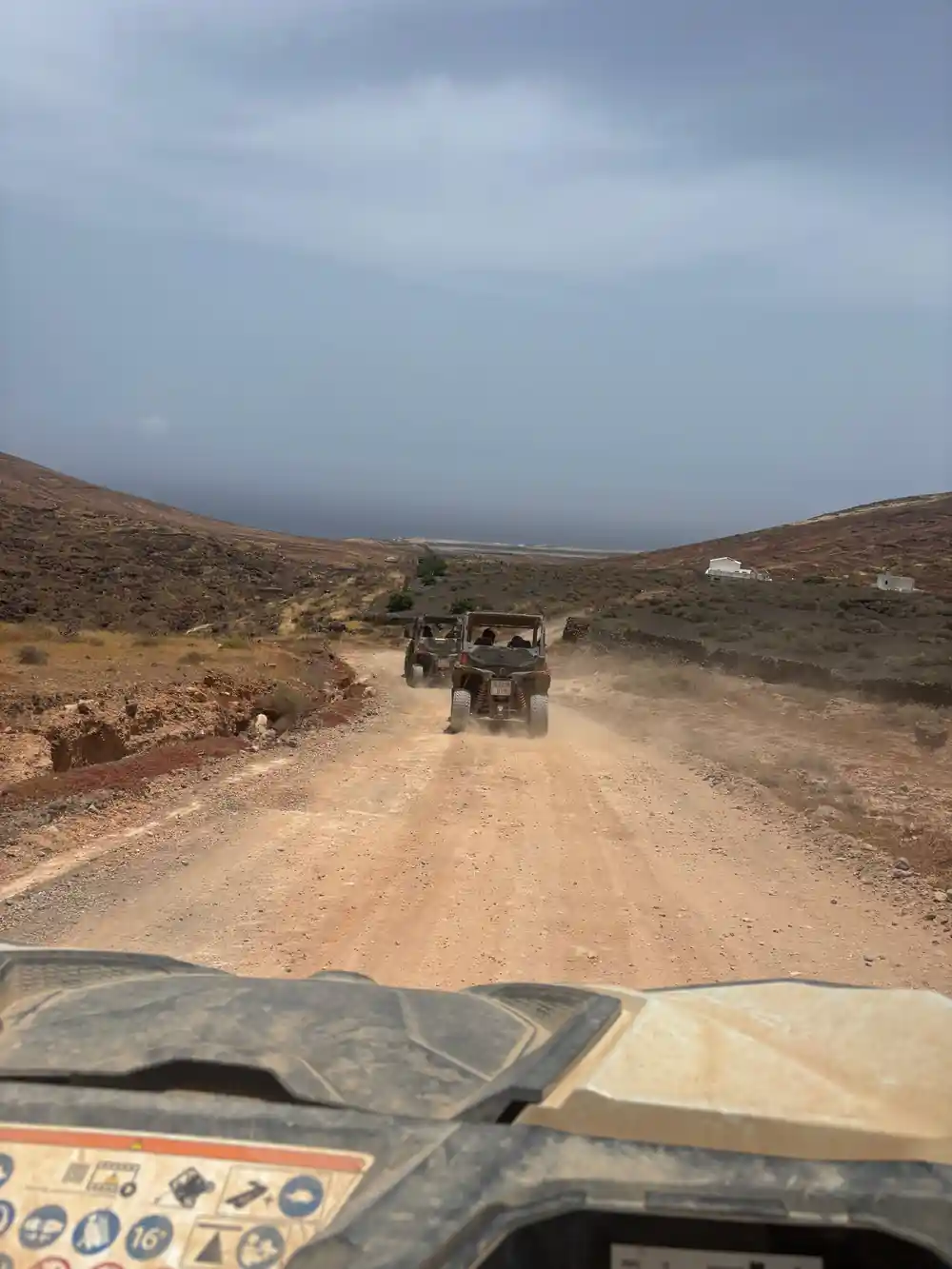 Buggy on sandy track driving downhill toward misty coast