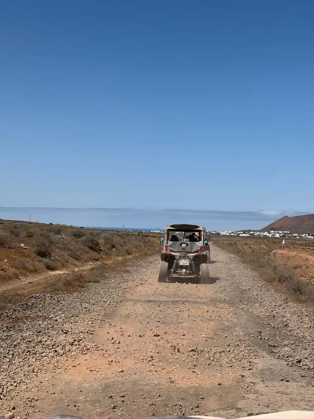 Buggy vehicle driving on gravel road toward coast