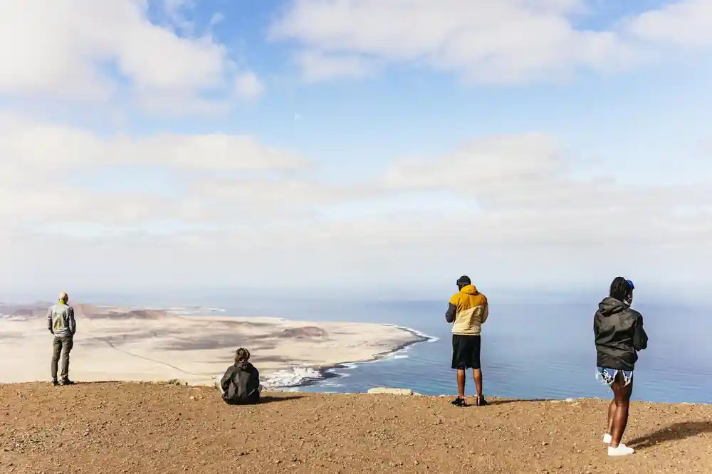 Hikers on volcanic ridge overlooking coastal landscape