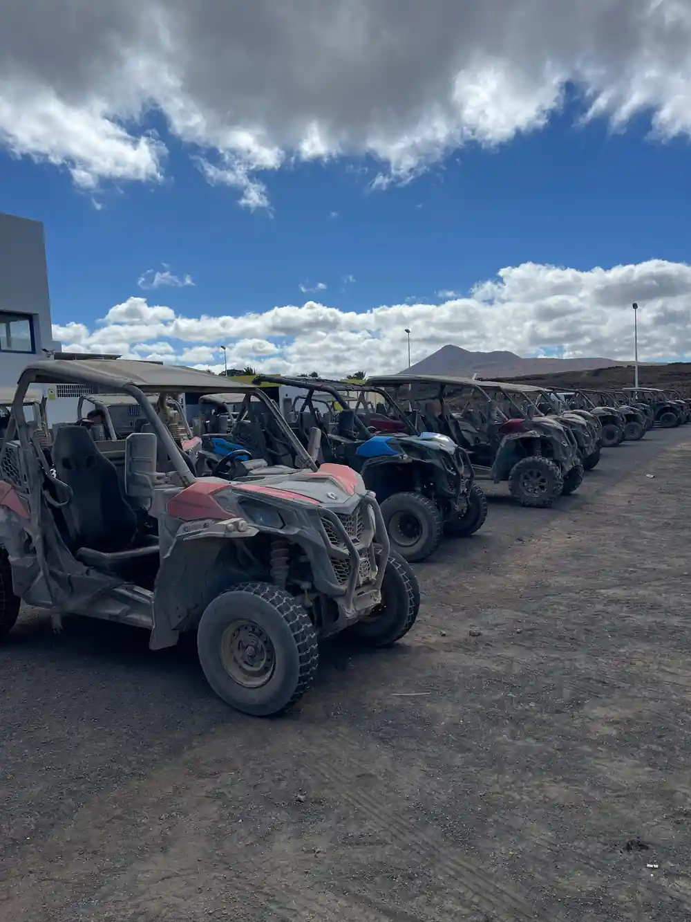 Multiple quad bikes parked in desert with volcano backdrop