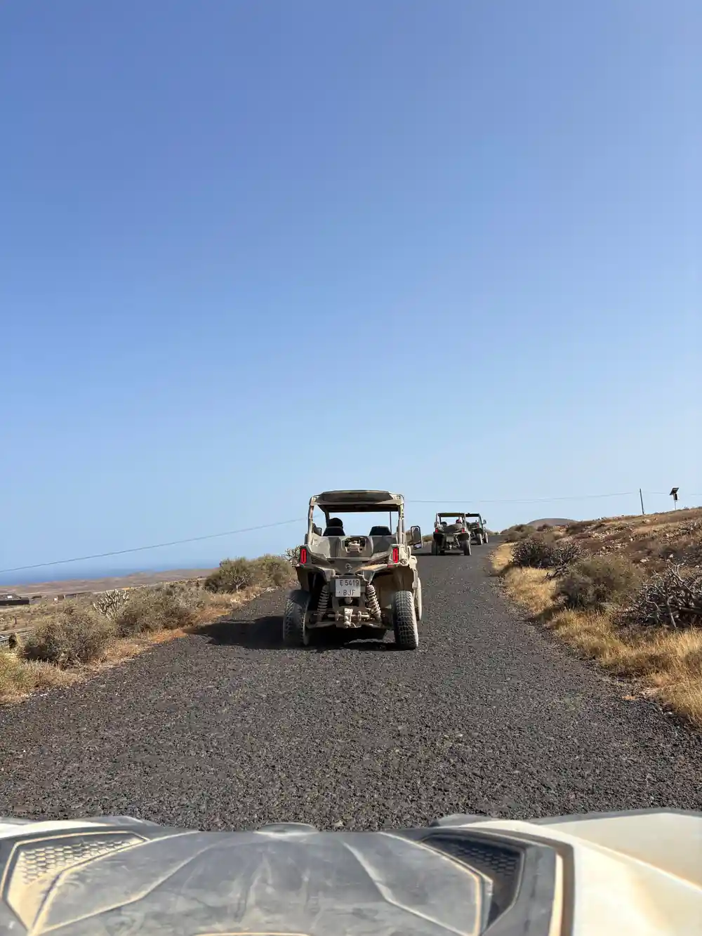 Off-road buggy driving on paved road through desert landscape