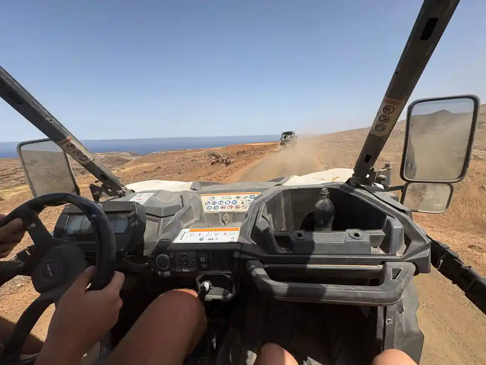 Person driving off-road buggy across arid volcanic terrain