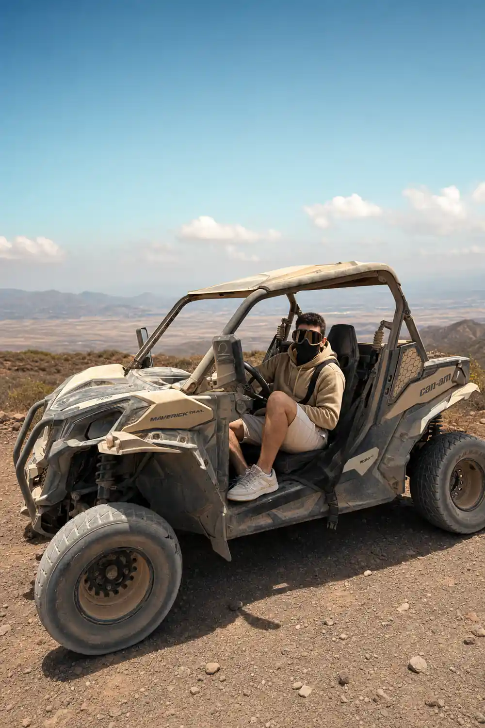 Person in grey shirt sitting in white buggy on sandy terrain