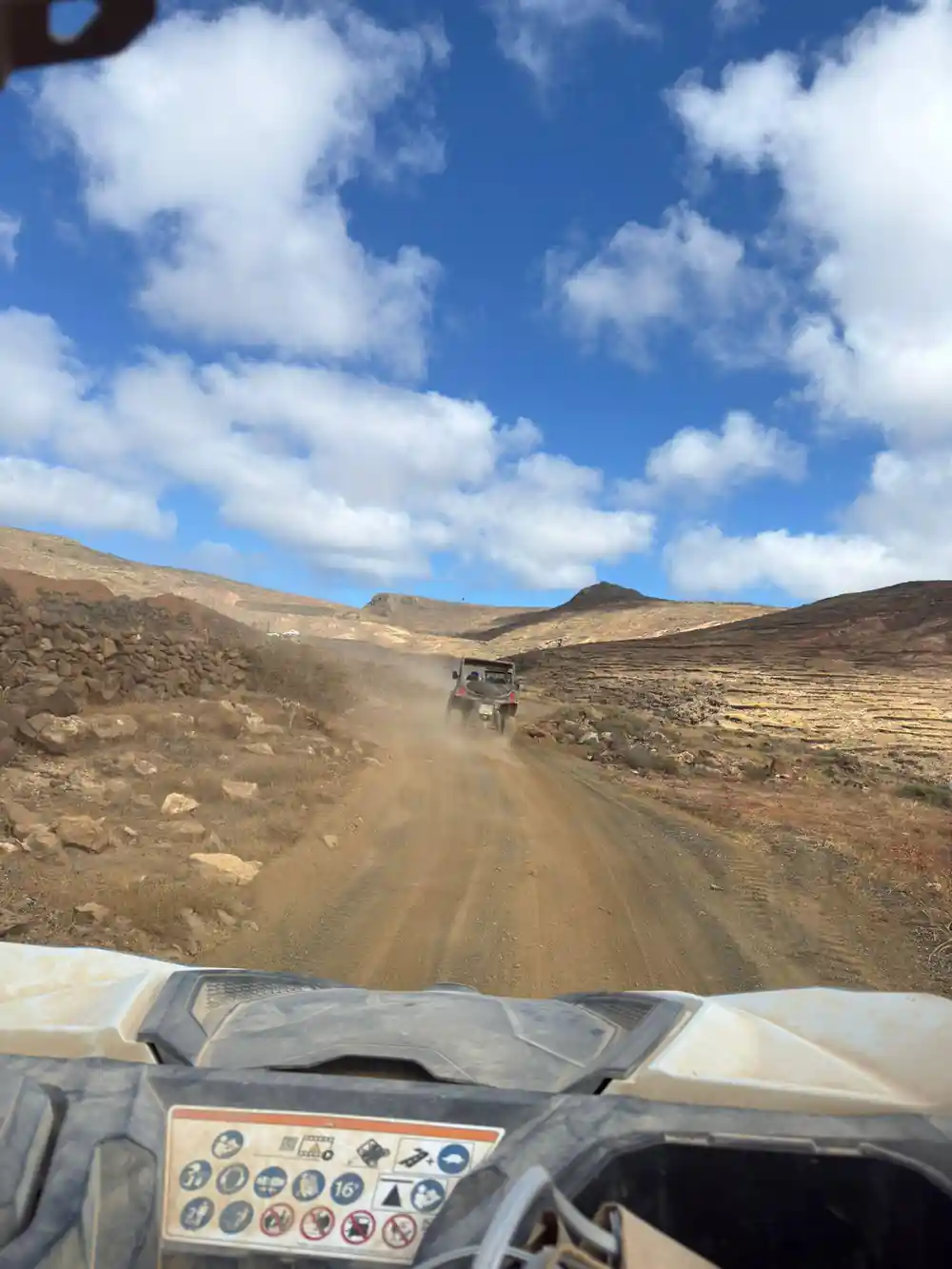 Quad bike on dirt road across barren volcanic landscape