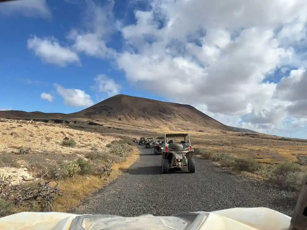 Quad bike driving on rocky road toward dark volcano