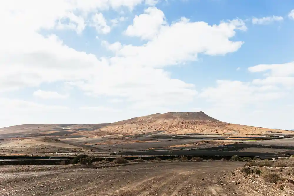 Single dark volcanic cone mountain in arid landscape