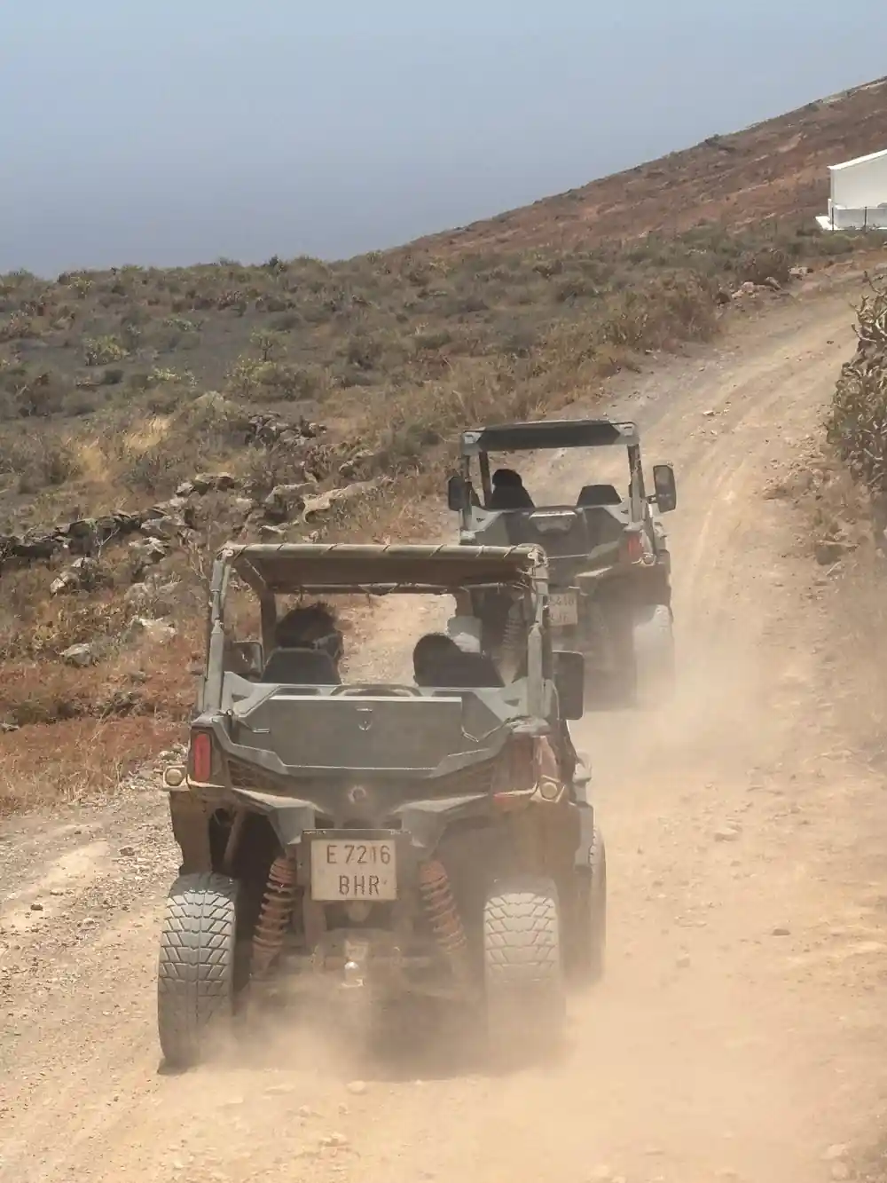Two all-terrain vehicles driving on dusty mountain road