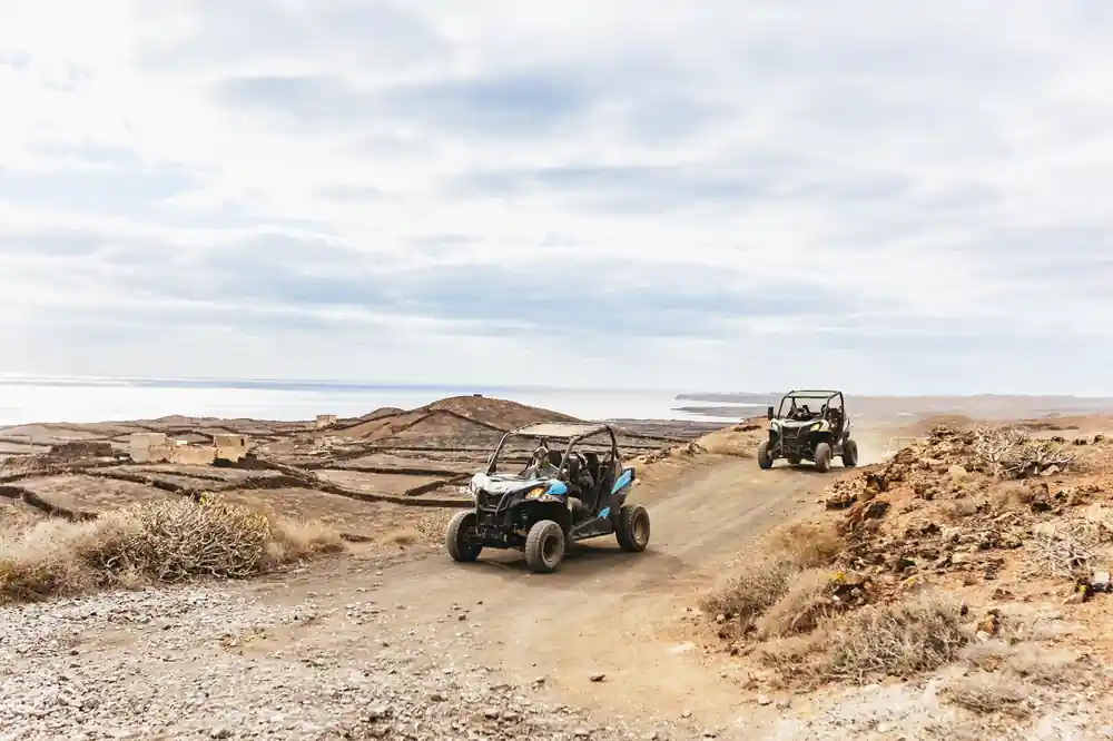 Two buggies on dirt road across arid plateau landscape