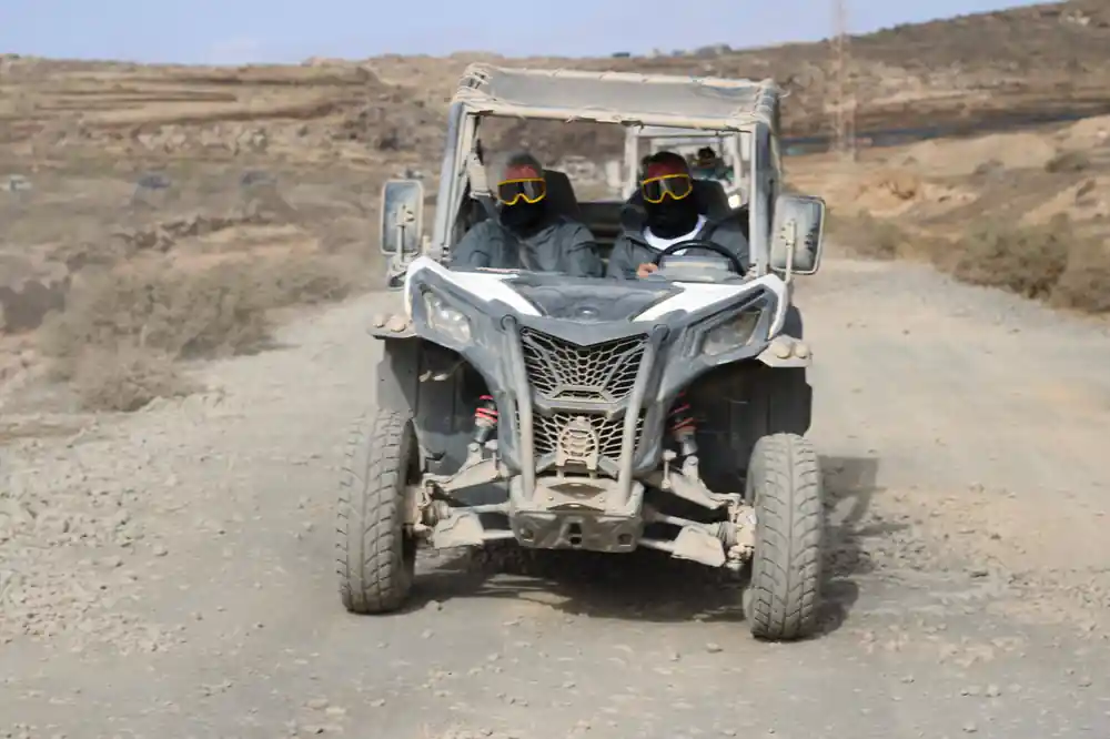Two people in buggy on gravel desert landscape