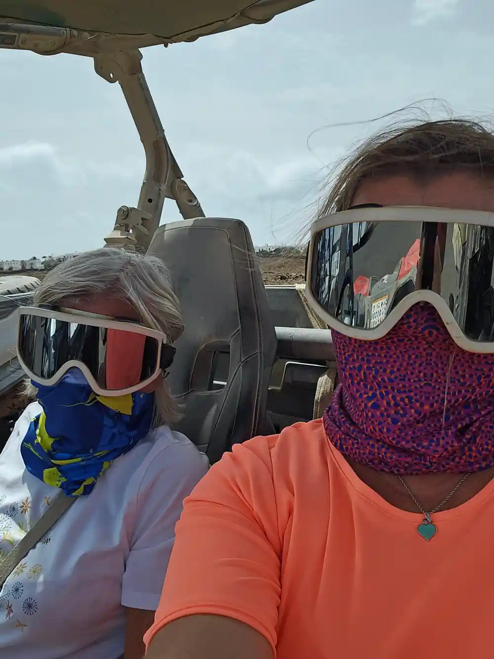 Two people wearing goggles in open buggy vehicle