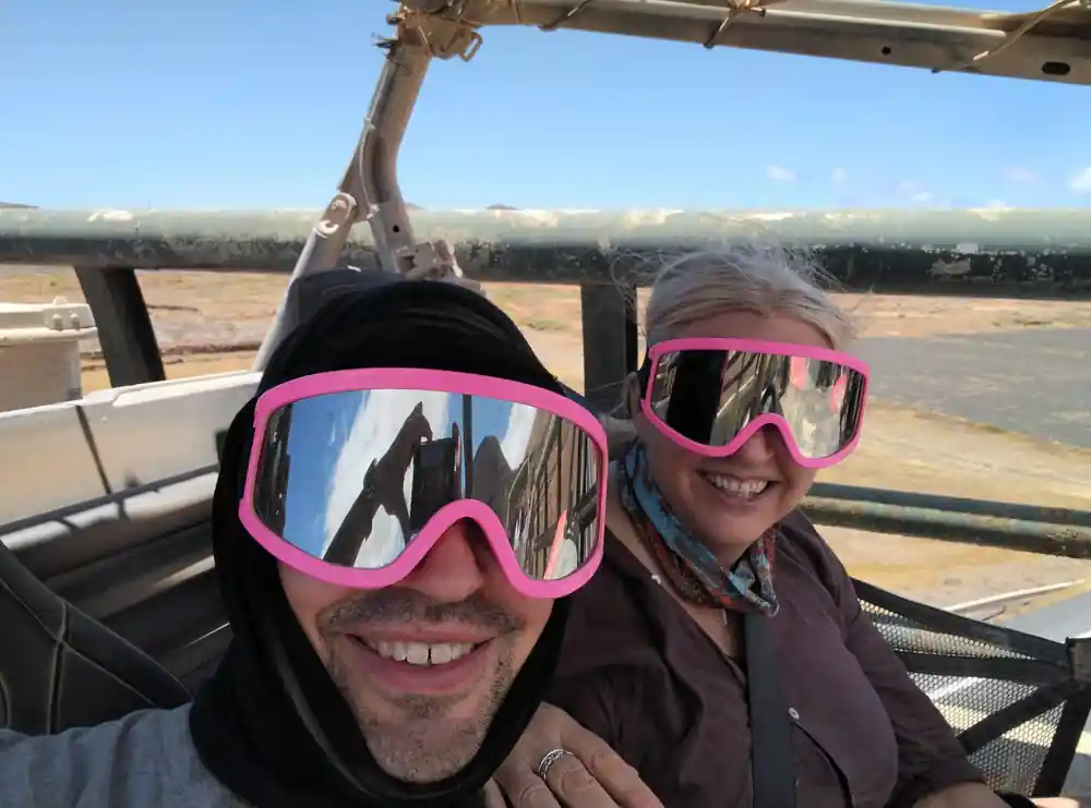 Two people wearing pink goggles smiling in buggy cockpit