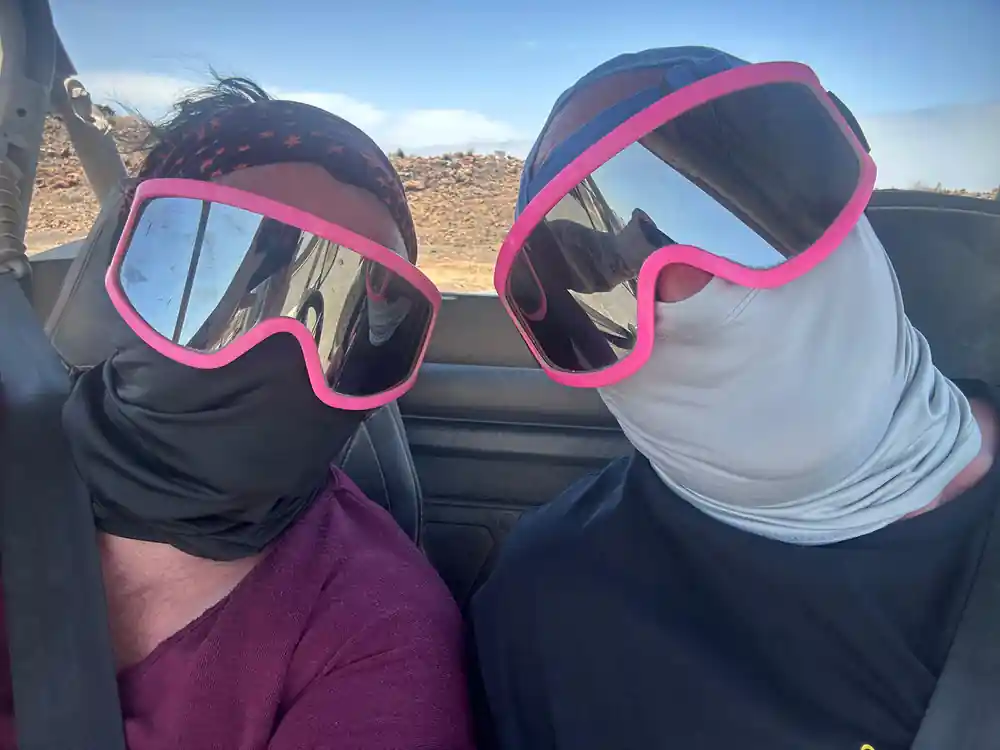 Two people wearing pink ski goggles in vehicle