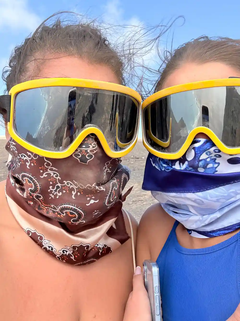 Two people wearing yellow ski goggles and masks