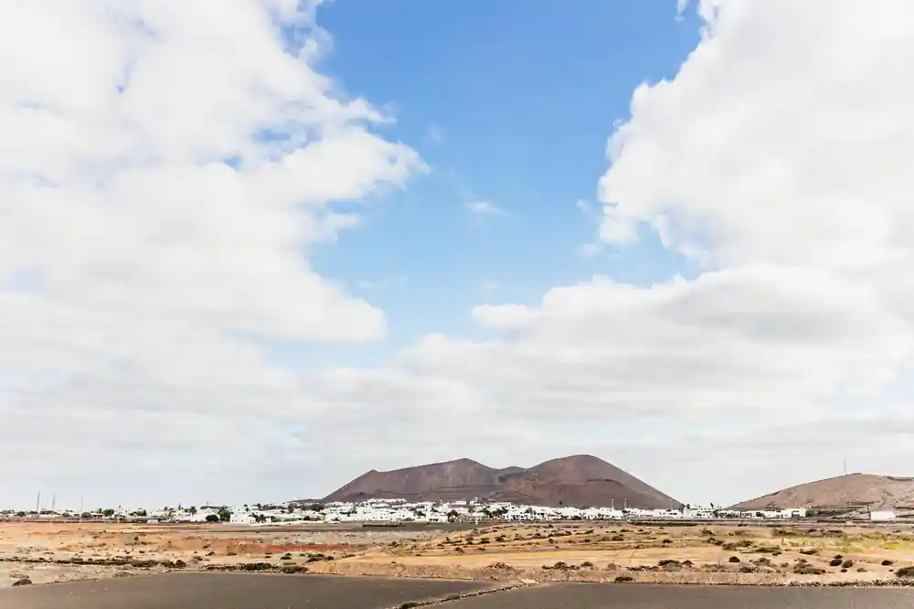 Volcanic mountains above coastal town with sparse vegetation